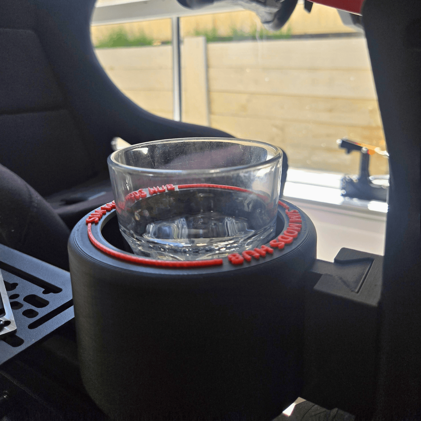 F1-Style Cup Holder for Sim Rigs holding a glass, designed for optimal hydration in racing setups.